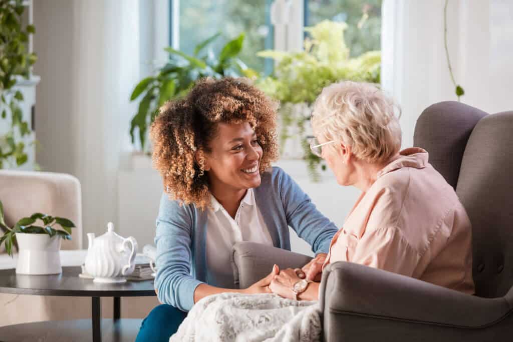 Woman holds hand with senior elderly woman at a senior living community