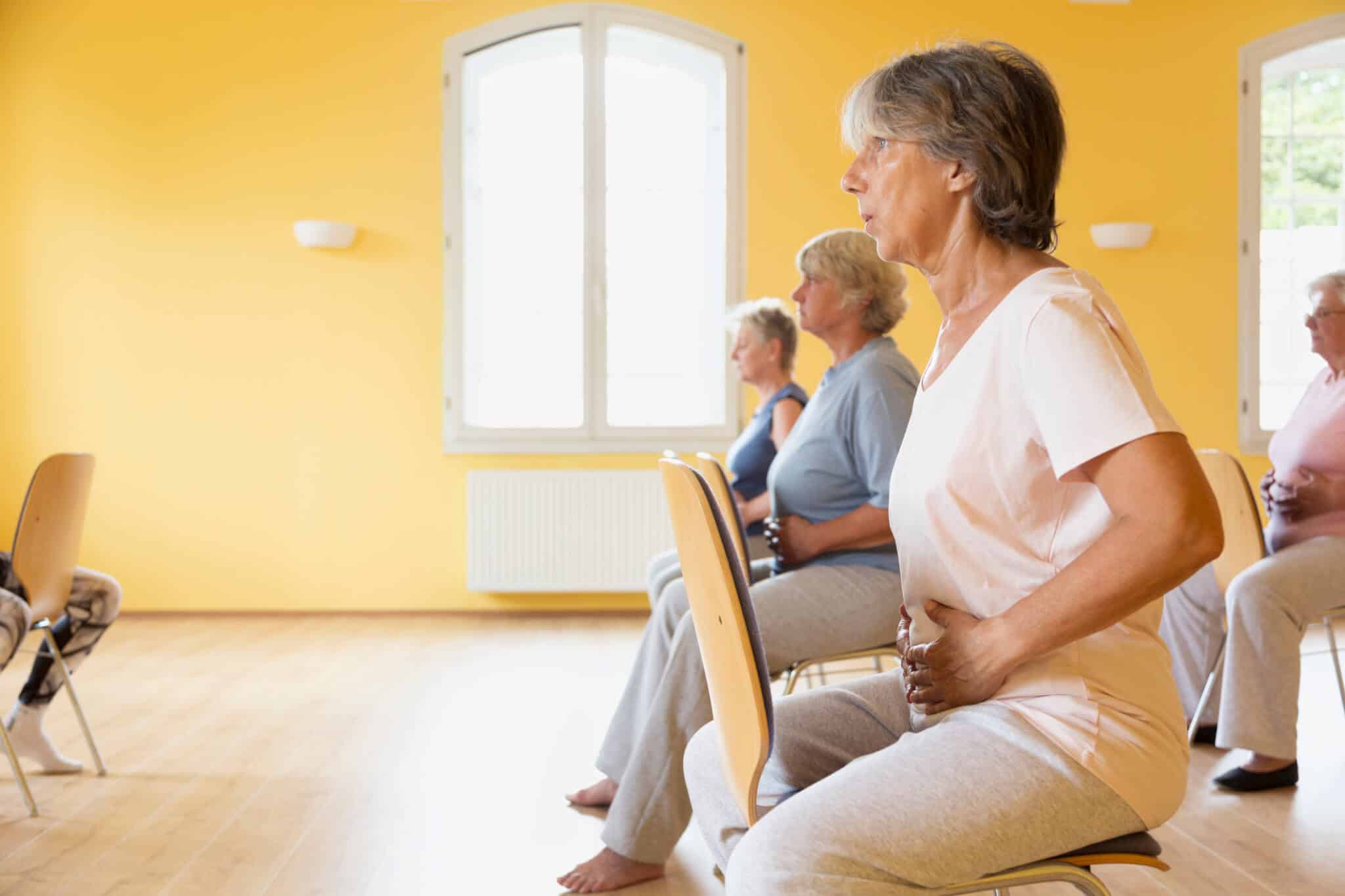 senior practicing chair yoga