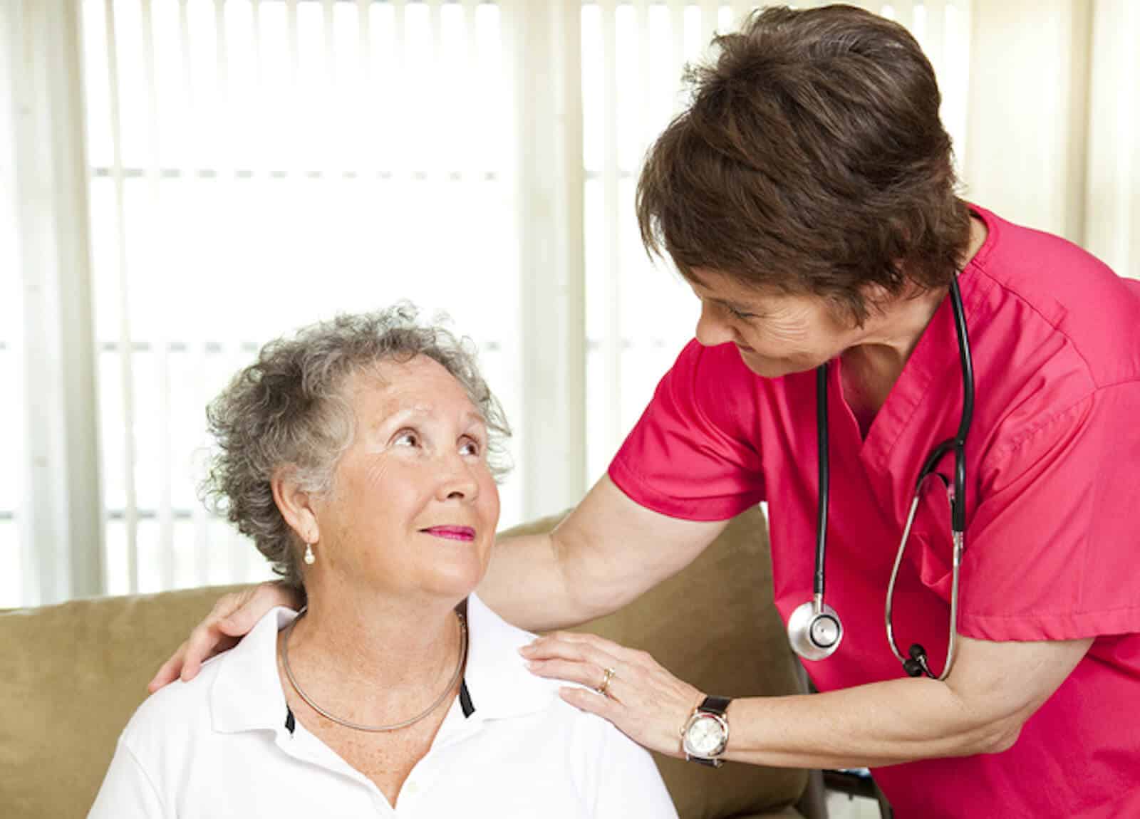 A nurse helps a senior woman at an assisted living facility