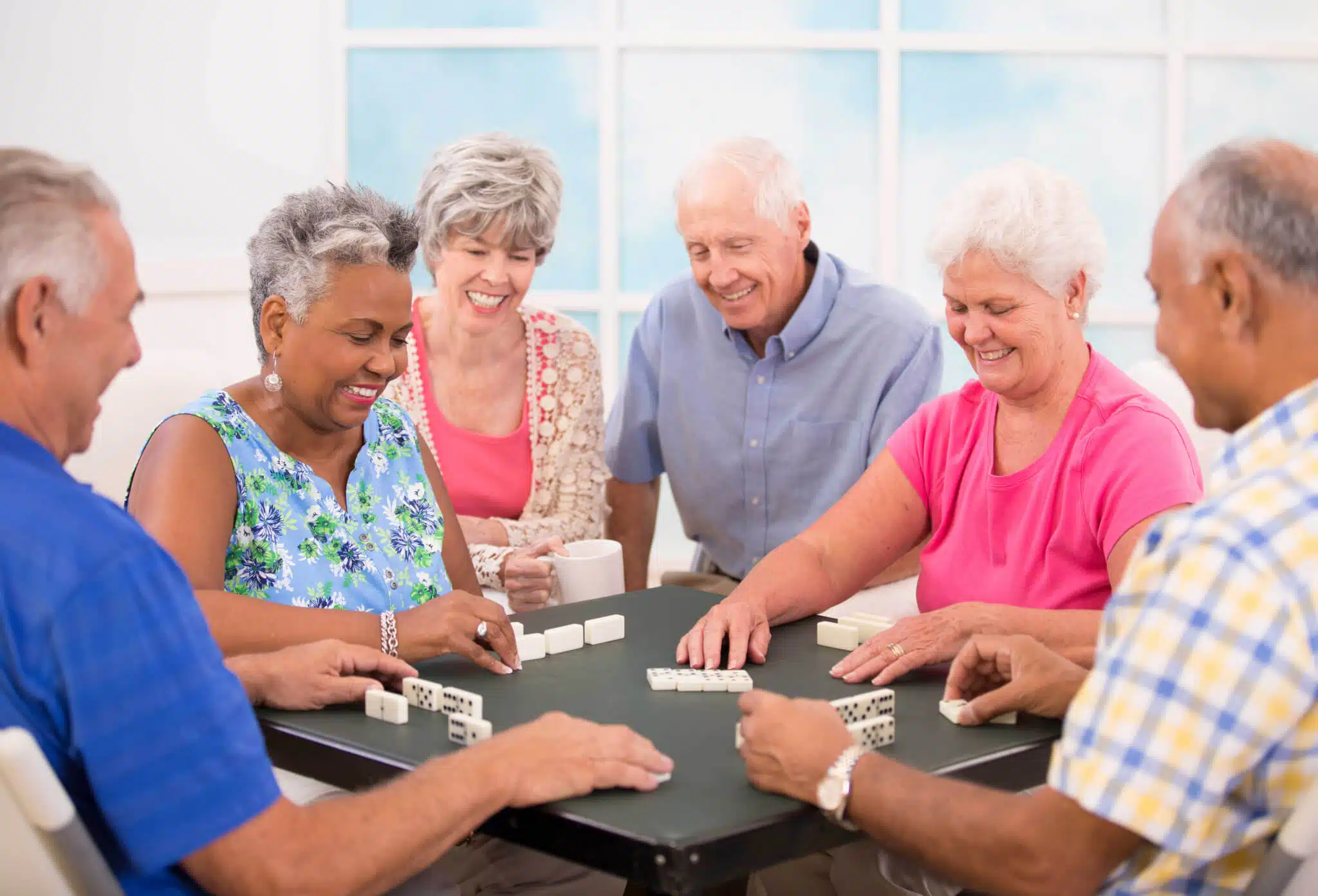 group of 6 elderly people having fun playing dominos