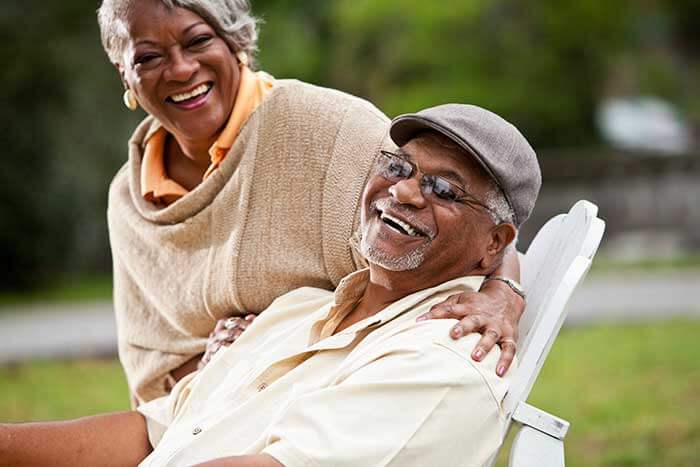 A senior couple smiling and posing for the camera while enjoying the outdoor weather